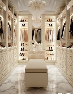 a walk in closet filled with lots of white furniture and chandelier hanging from the ceiling