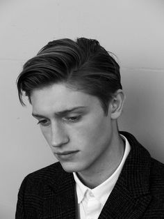 black and white photograph of a young man in a suit looking at his cell phone