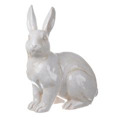 a white ceramic rabbit figurine sitting on the ground