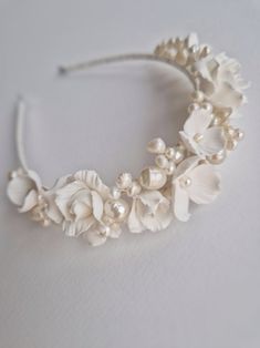 a white headband with flowers and pearls on the side is laying on a table