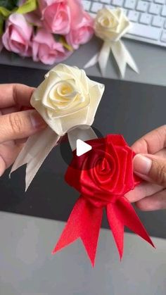 two hands holding red and white roses on top of a computer desk next to a keyboard