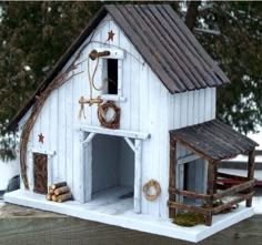 a small white building with a horse stable on the roof and door open to let people inside