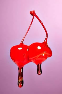 a red object hanging upside down on a purple background with water dripping from the bottom