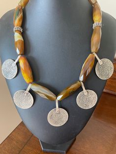 A very striking necklace made from a collection of 5 worn coins turned into pendants. The coins appear to be Moroccan and have the Islamic calendar date on them of 1320 (1903) The coins are about 2.5cm across and they make a very striking collar effect with the caramel coloured faceted agate beads. The agates are cut to be quite glittery although in earth tones. Moroccan Coin Necklace, Islamic Calendar, Calendar Date, Caramel Color, Agate Beads, Faceted Bead, Earth Tones, Agate, Beaded Necklace