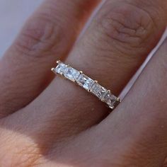 a woman's hand with a diamond ring on top of her finger and the band is