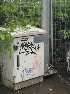 an old refrigerator with graffiti on it next to a fence