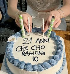 a woman holding two candles over a cake with the number twenty seven on it,