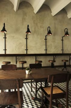 an empty restaurant with wooden tables and chairs in front of a wall mounted light fixture