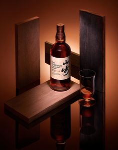 a bottle of whisky sitting on top of a wooden table next to a glass filled with liquid