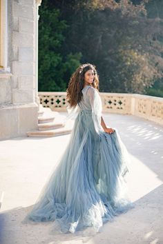 a woman in a blue dress is standing outside