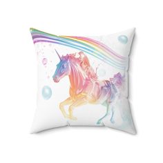 a white pillow with a rainbow unicorn on it