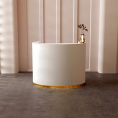 a white round table with gold accents in front of a wall and window sill