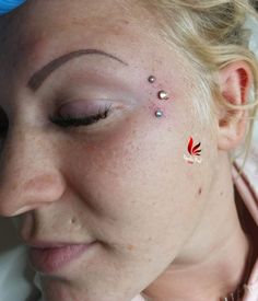 a close up of a person with tattoos on her face and nose, looking at the camera