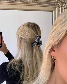 a woman taking a selfie in front of a mirror with her hair styled into a pony tail