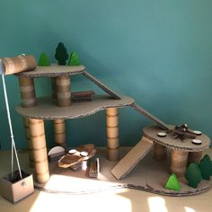 a cat house made out of cardboard with trees on the top and other items around it