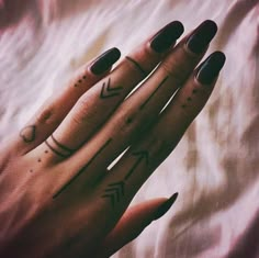 a woman's hand with two tattoos on it and an arrow tattooed on the middle finger