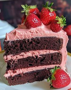 a piece of chocolate cake with pink frosting and strawberries on the top slice