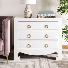 a white chest of drawers sitting next to a purple chair