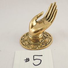 a golden hand statue on top of a table next to a note with the number five