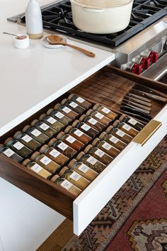 an open drawer in a kitchen filled with spices and seasonings next to a stove