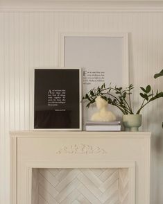 a white fireplace with some plants and pictures on it