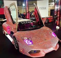 a pink car with its hood open on display