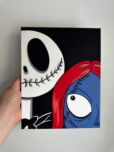 a person holding up a painting with a skeleton and red hair on it's face