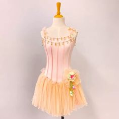 a pink and yellow dress on a mannequin with flowers in the skirt,