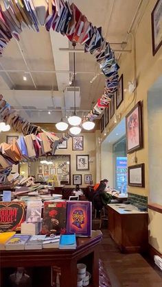 the inside of a clothing store with lots of shirts hanging from the ceiling and pictures on the walls