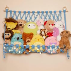 a bunch of stuffed animals are on a blue shelf with stringing around it and hanging from the wall