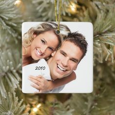 a christmas ornament hanging from a tree with a couple on it's back