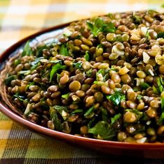 a bowl filled with lentils and greens on top of a checkered table cloth