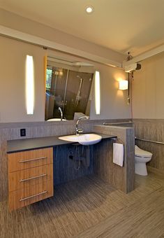 a bathroom with a sink, toilet and mirror in it's own area is shown