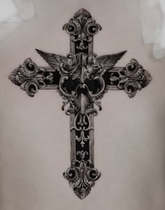 a cross tattoo on the back of a woman's lower body, with an ornate design