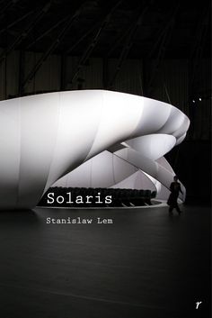 a large white structure in the middle of a building with people walking around it and there is a man standing next to it