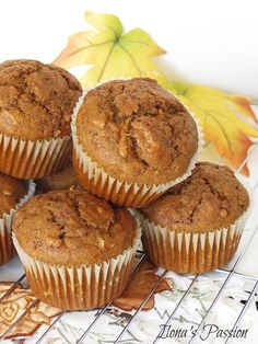 a bunch of muffins sitting on top of a cooling rack next to leaves