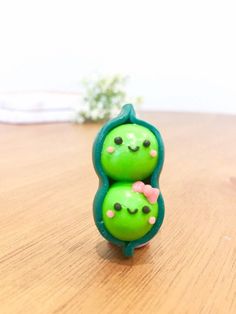 two green toy figures sitting on top of a wooden table