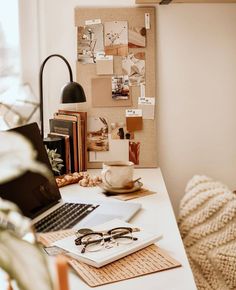 a laptop computer sitting on top of a white desk next to a cup of coffee