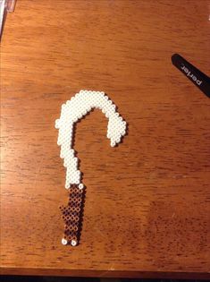 a piece of bead art that looks like a question mark on a wooden table