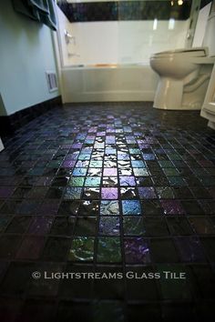 a bathroom with a toilet, sink and bathtub covered in multicolored glass tiles