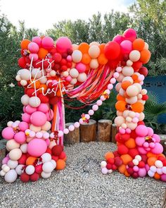 an arch made out of balloons and streamers with the word love spelled on it