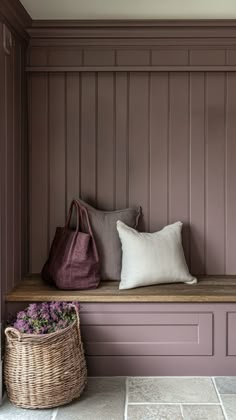 a bench with some pillows on it and a basket in the corner next to it