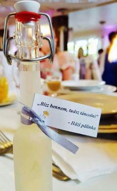 a bottle with a label on it sitting on a table next to plates and silverware