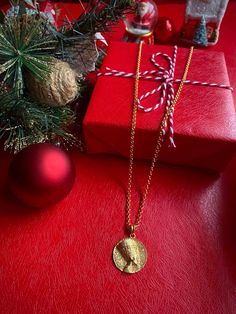 a red table topped with christmas presents and a gold plated necklace on top of it