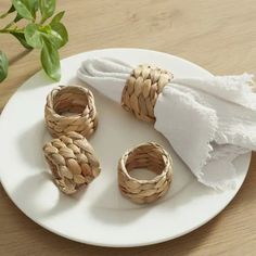 three napkin rings sitting on top of a white plate next to a green leafy plant