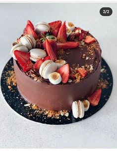 a chocolate cake topped with strawberries and seashells on a black platter