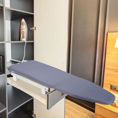 a blue ironing board sitting on top of a white shelf next to a tv