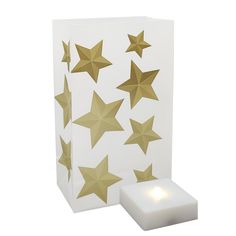 a white box with gold stars on it and a lit candle in the bottom corner