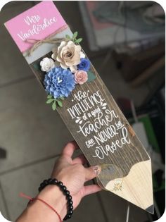 a person holding up a wooden sign with flowers on it