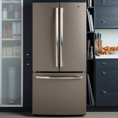 a metallic refrigerator freezer sitting in a kitchen next to an open book shelf with books on it